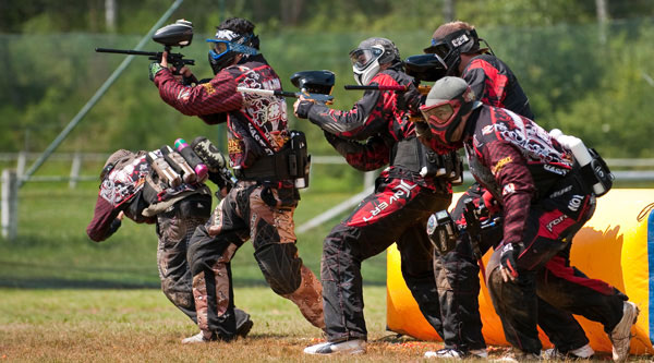 Men paying paintball on an outdoor field in Riga, Latvia